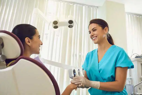 Dentist holding hand of patient sitting in dental chair